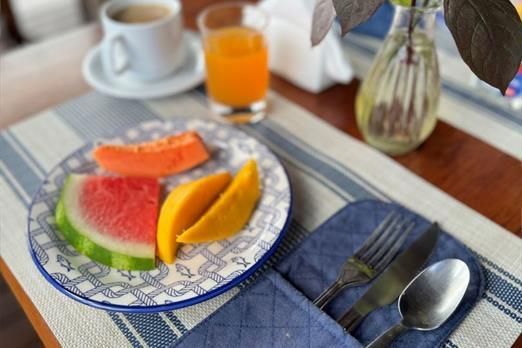 Um prato de frutas e uma xícara de café em uma mesa
