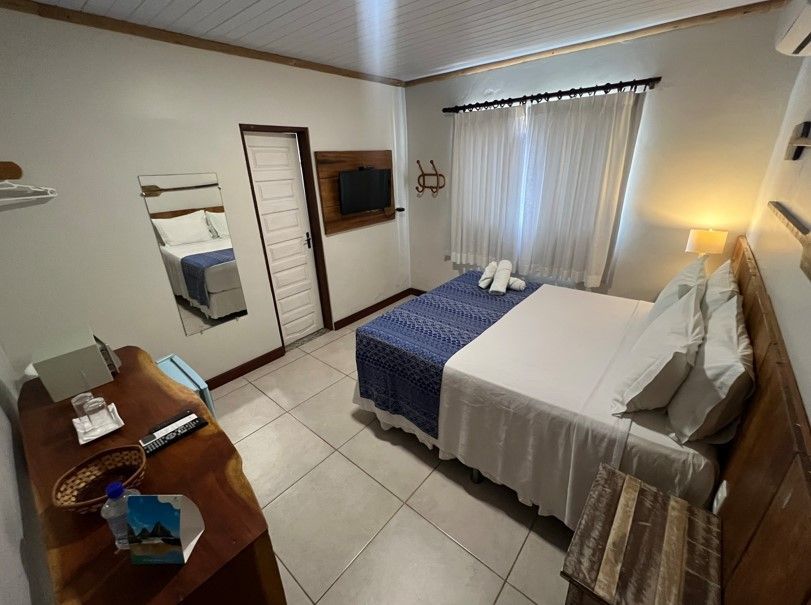 Um quarto de hotel com uma cama grande e uma televisão.