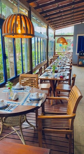 Um restaurante com mesas e cadeiras e muitas janelas.