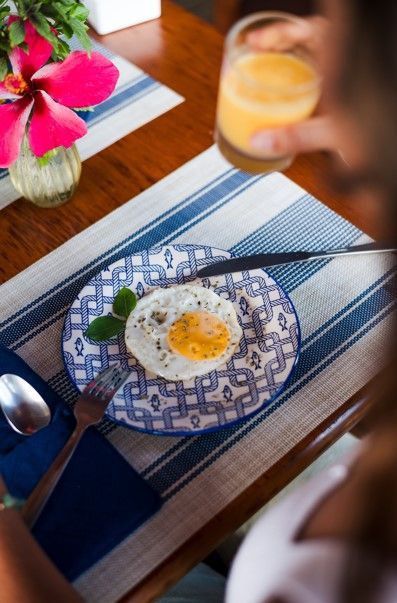 Uma pessoa está sentada à mesa com um prato de comida e um copo de suco de laranja.