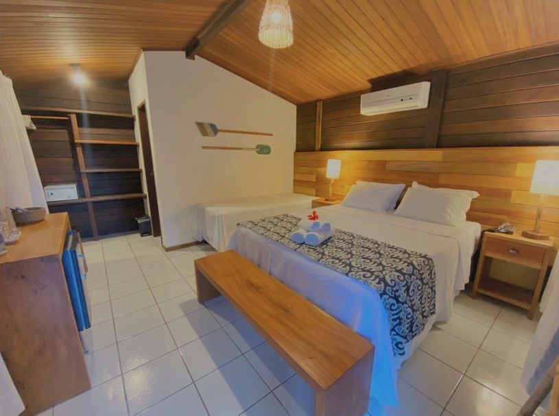 Um quarto de hotel com uma cama king size e um banco.