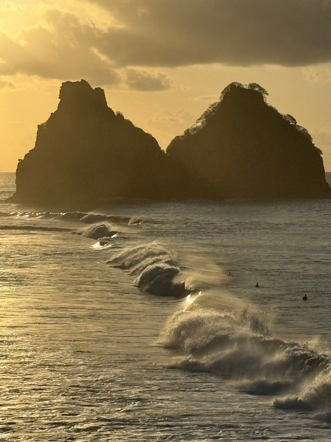 Um pôr do sol sobre um corpo de água com pedras ao fundo