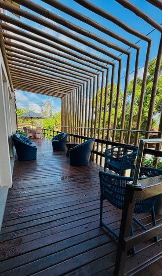 Um deck de madeira com cadeiras e uma pérgola.