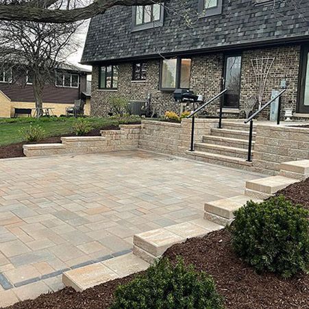 A stylish backyard patio with multi-level retaining walls, wide steps, and a spacious paver layout. The outdoor space blends function and aesthetics for a perfect entertainment area.