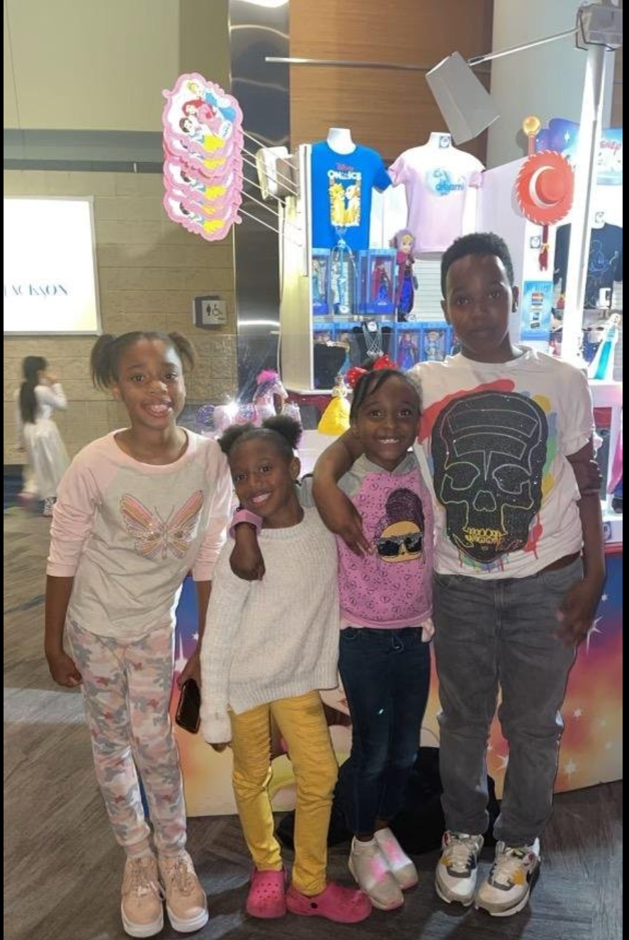 A group of children are posing for a picture in front of a store.