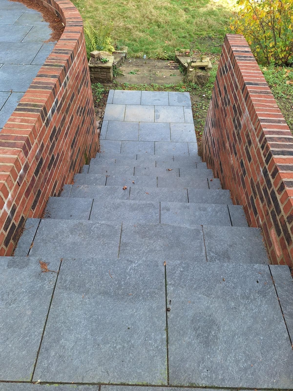 Stone steps descend between red brick walls.
