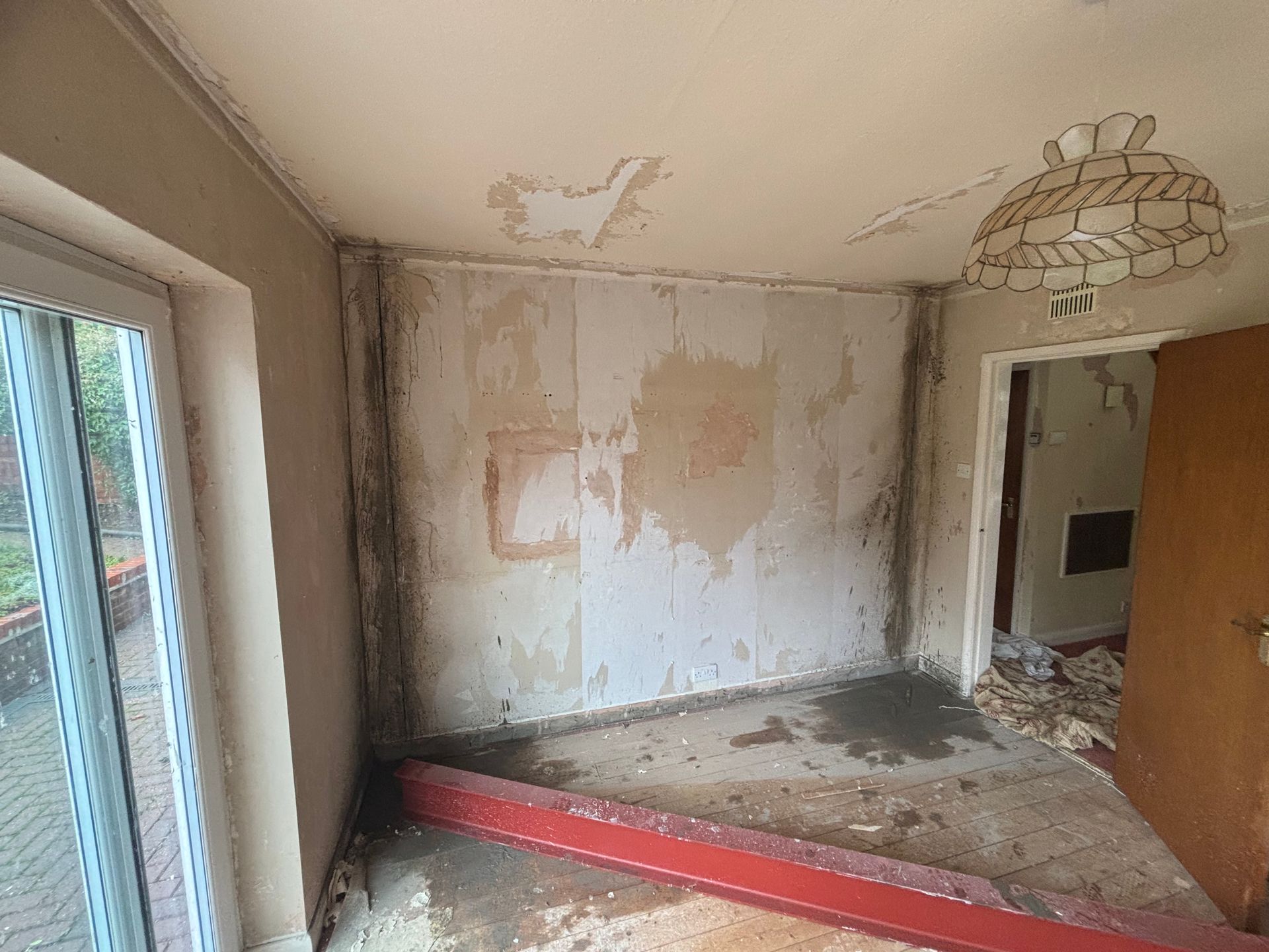 Room with peeling paint and water damage. Walls and ceiling show significant deterioration.