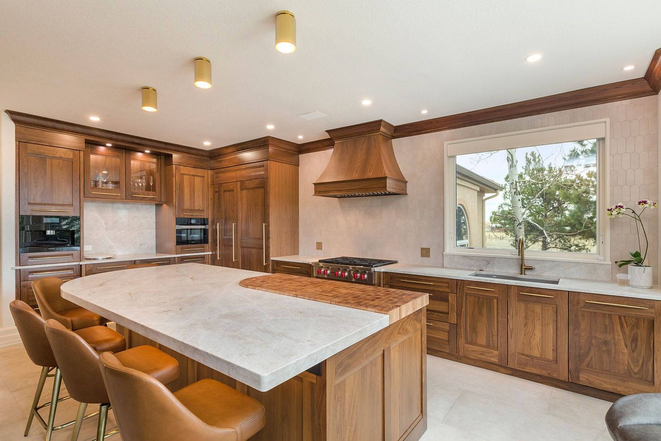 Luxury kitchen with wood cabinets, island with seating, and marble countertops.