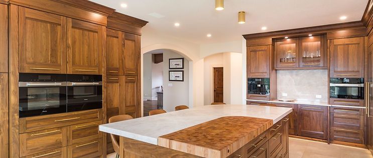 Wooden kitchen with a large island and two ovens.