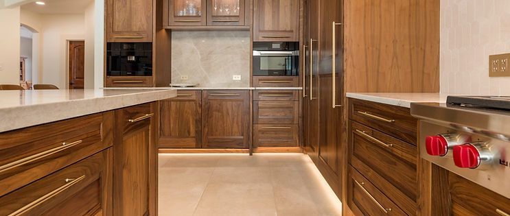 Wooden kitchen with built-in appliances and light-colored countertops.
