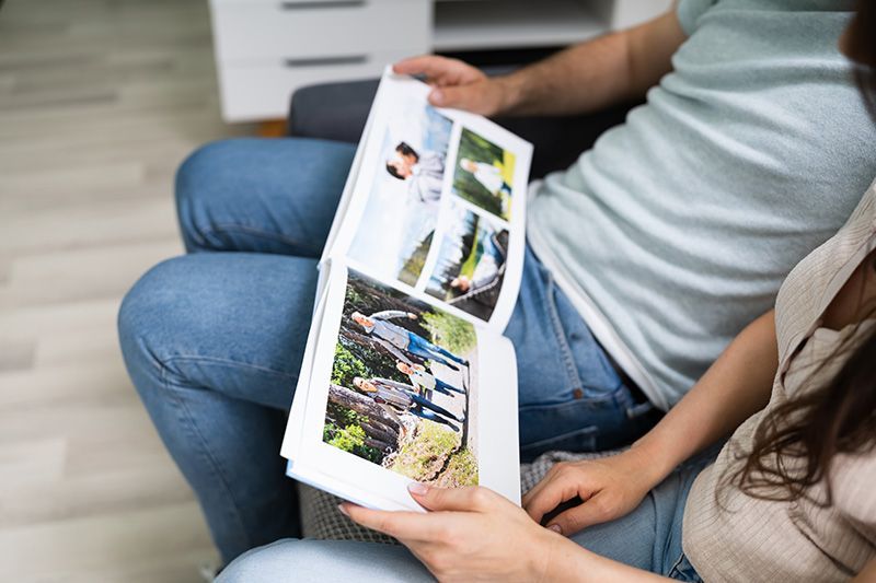 Couple sitting, looking at a photo album with colorful outdoor pictures.