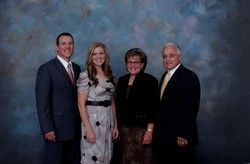 People posing in front of a blue mottled backdrop; all are formally dressed and smiling.