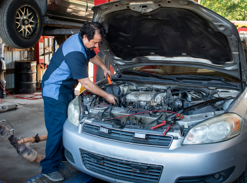 Mechanic inspecting a silver car with open hood in an auto repair shop | Best Auto Care