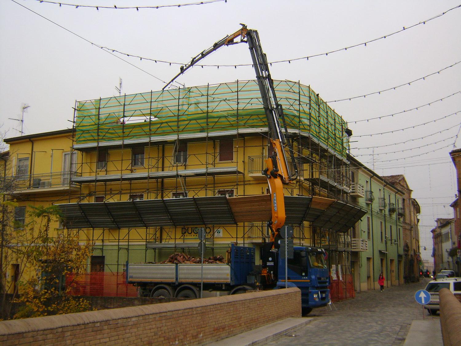 un camion e un’impalcatura davanti a un edificio giallo