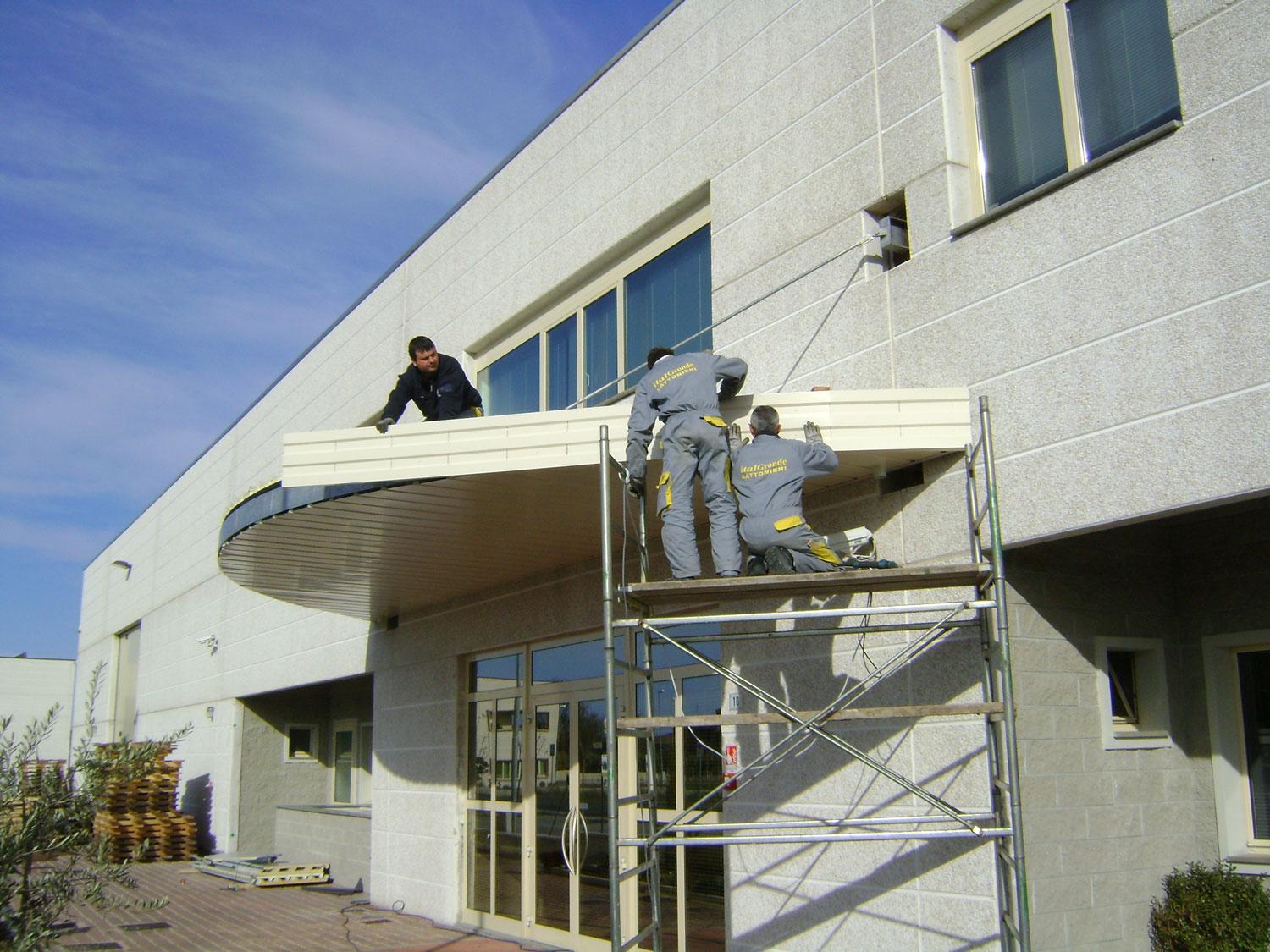 Due uomini su ponteggio al lavoro su tettoia