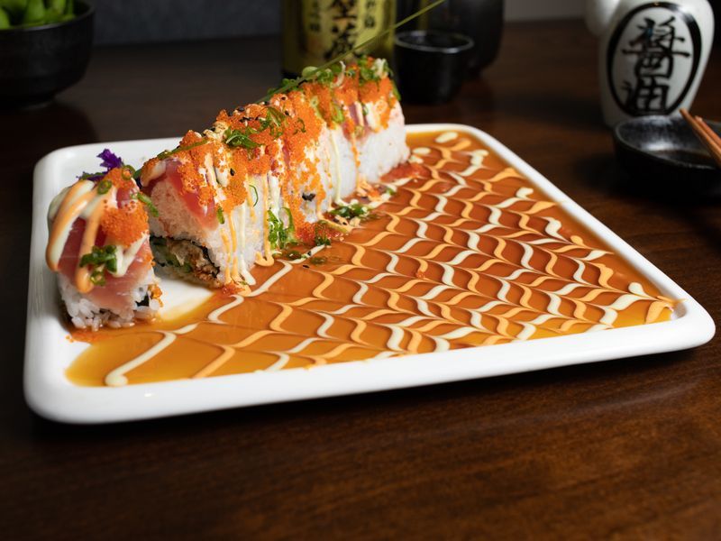 A white plate topped with sushi and sauce on a wooden table.