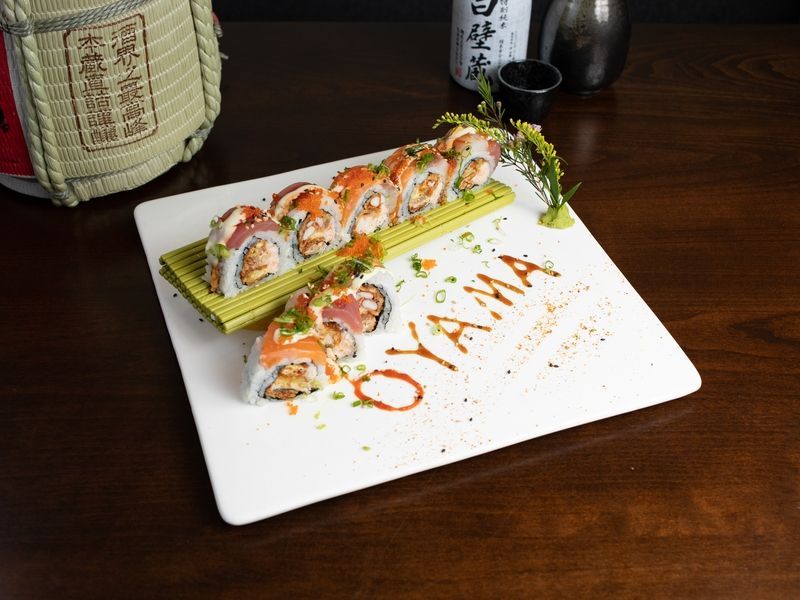 A white plate topped with sushi rolls on a wooden table.
