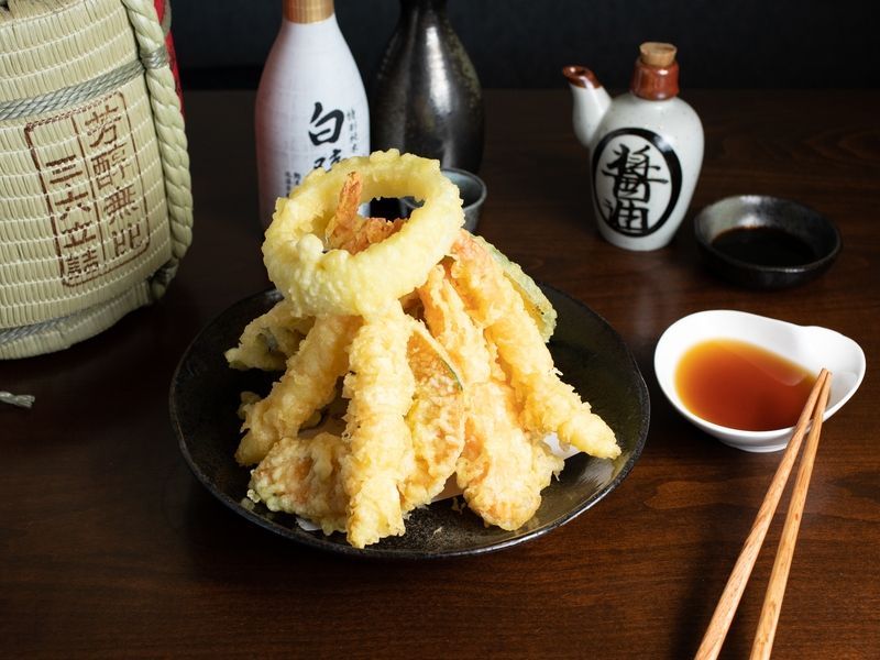 A plate of food with chopsticks and dipping sauce on a table.