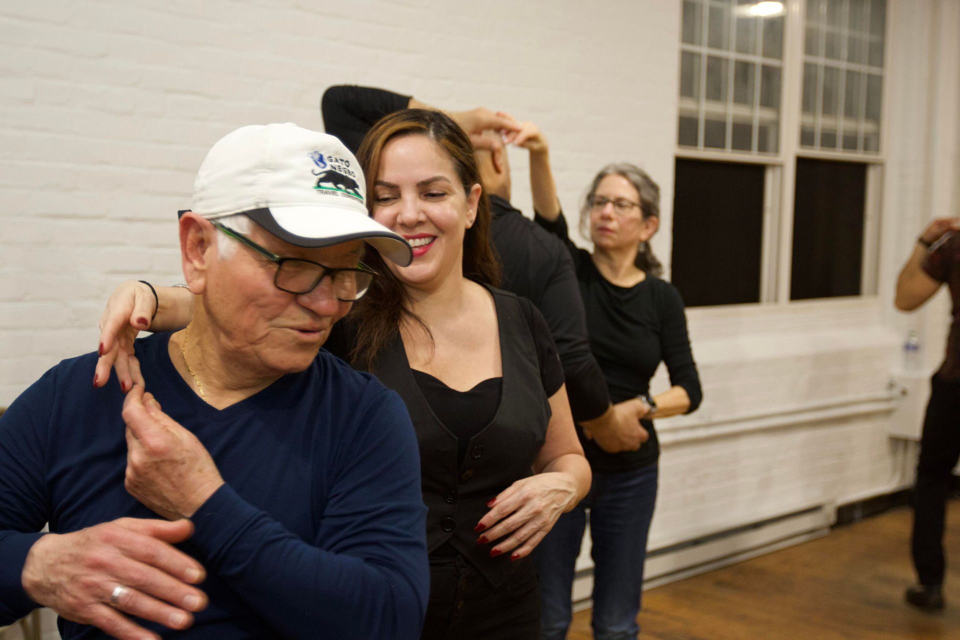 An older man leads his female dance partner into a spin during a salsa class. 