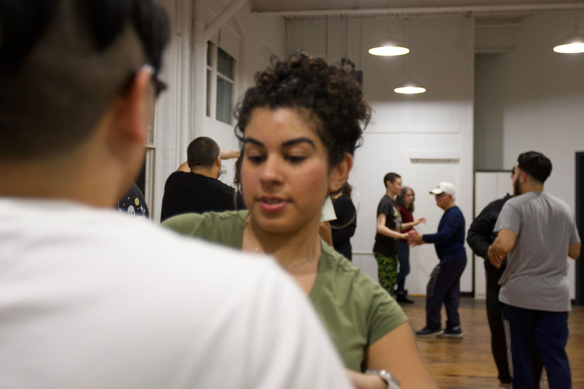 A female student concentrates on Bachata partner work choreography with her male dance partner.