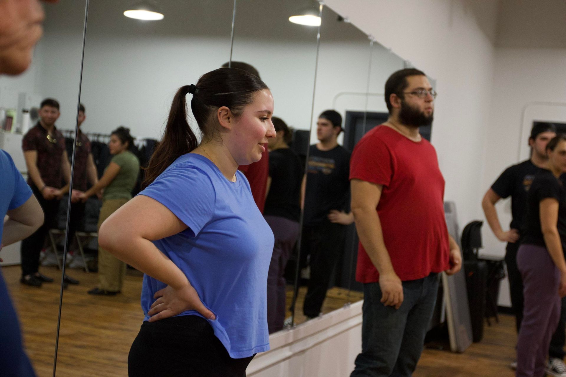 A female and male student watch their instructors demonstrate partner work choreography during a bachata class.