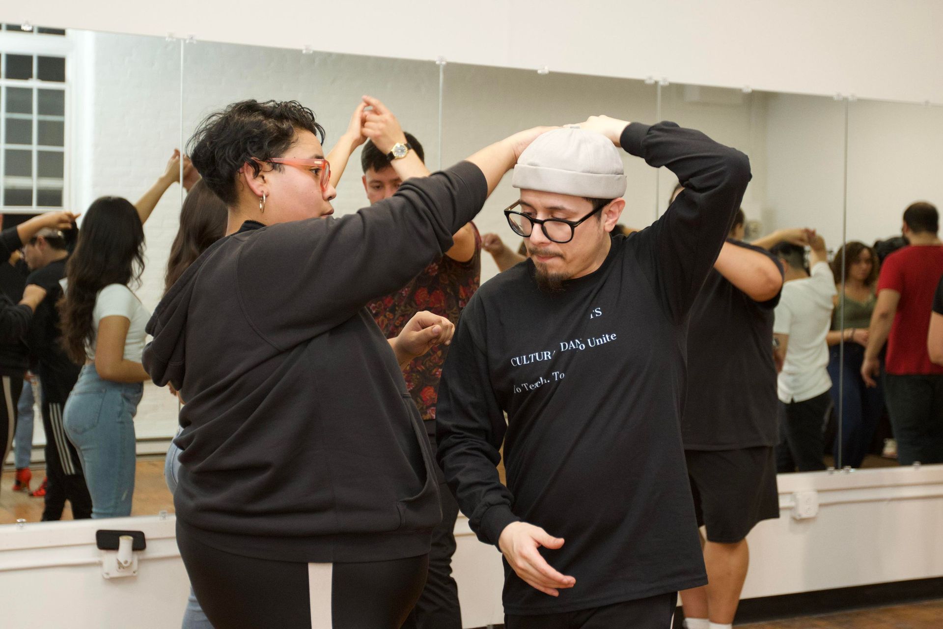 Instructor Brandon leads instructor Kristy's hand onto his shoulder.