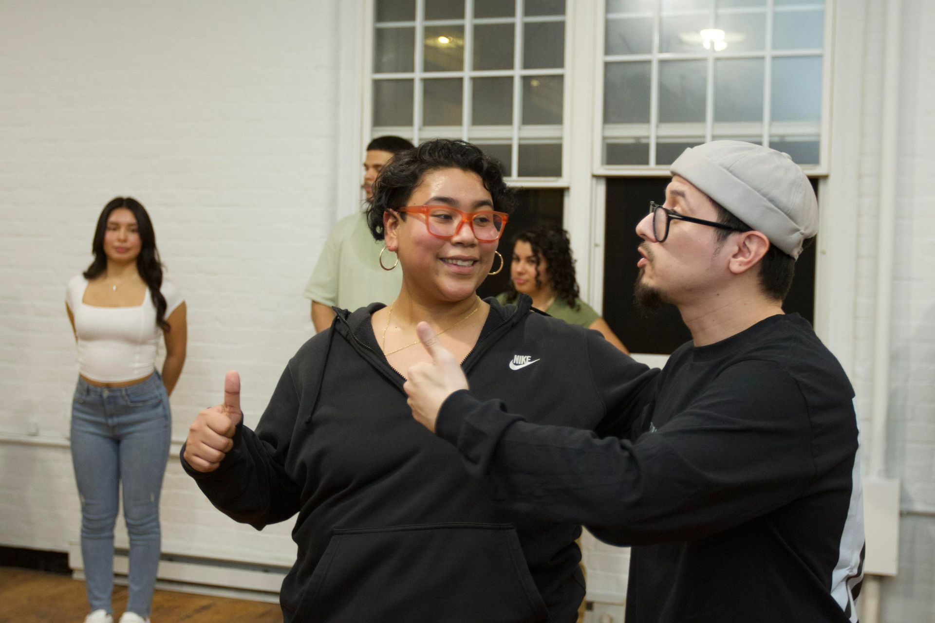 Instructor Brandon explains a dance move to his Bachata class while instructor Kristy gives a thumbs up.