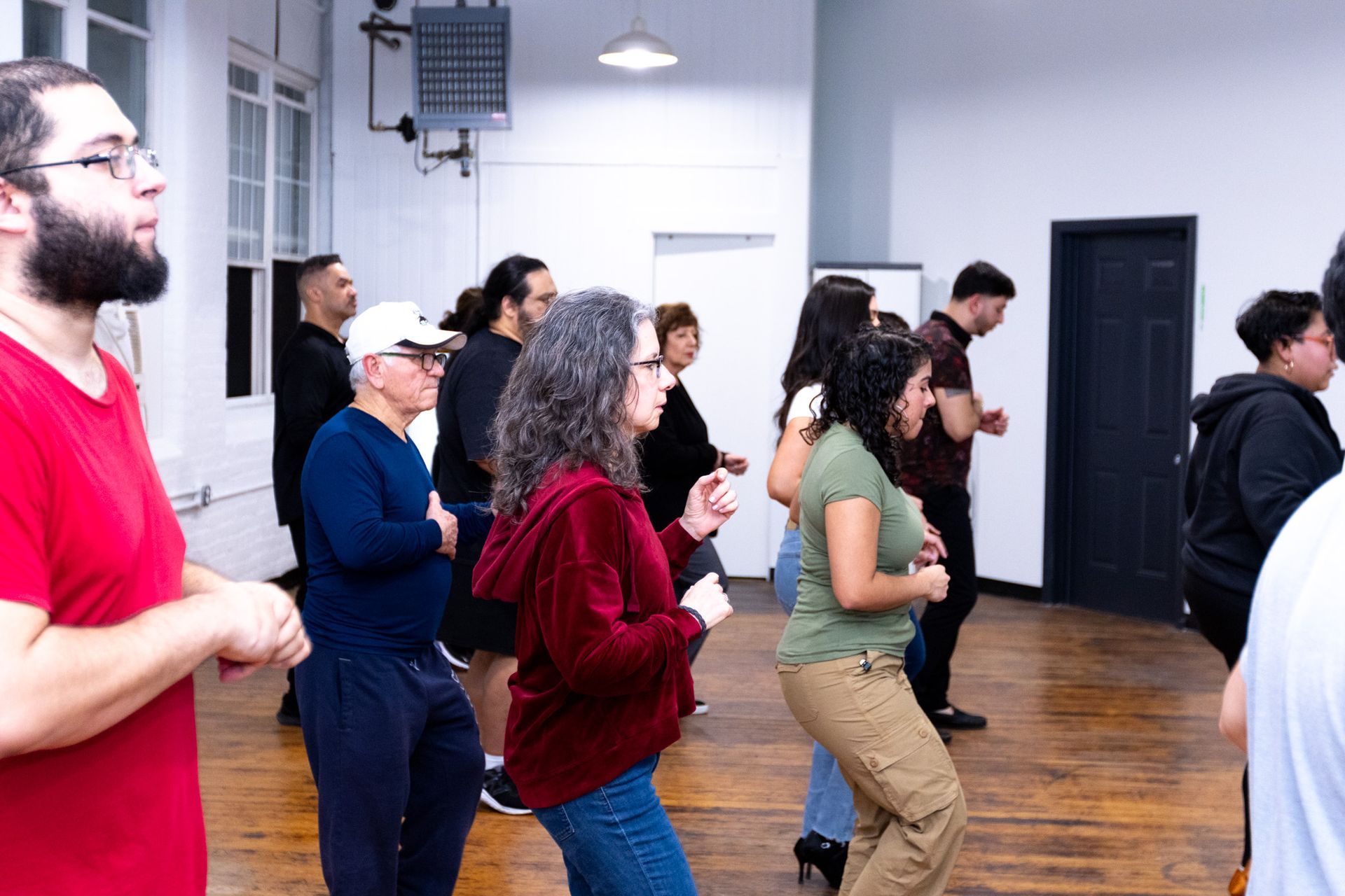 A group of young and older students follow their dance instructors' lead during a salsa class