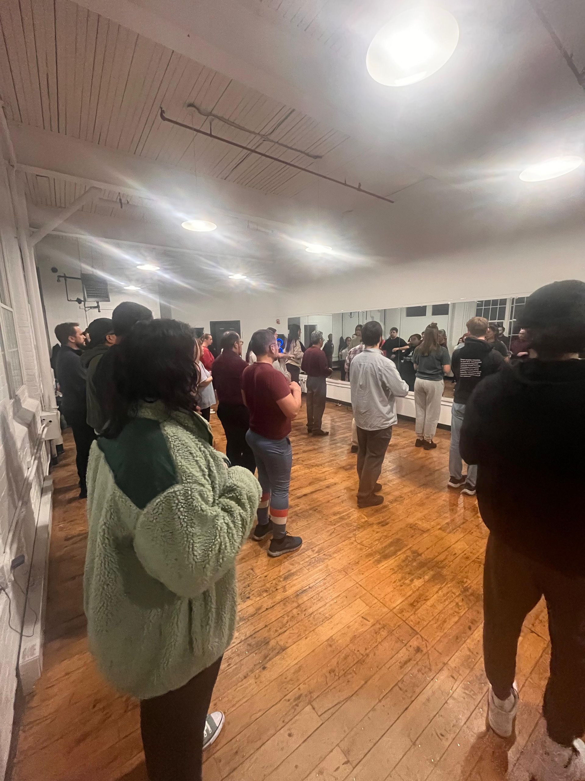 A large group of male and female students stand in lines as their dance class begins.