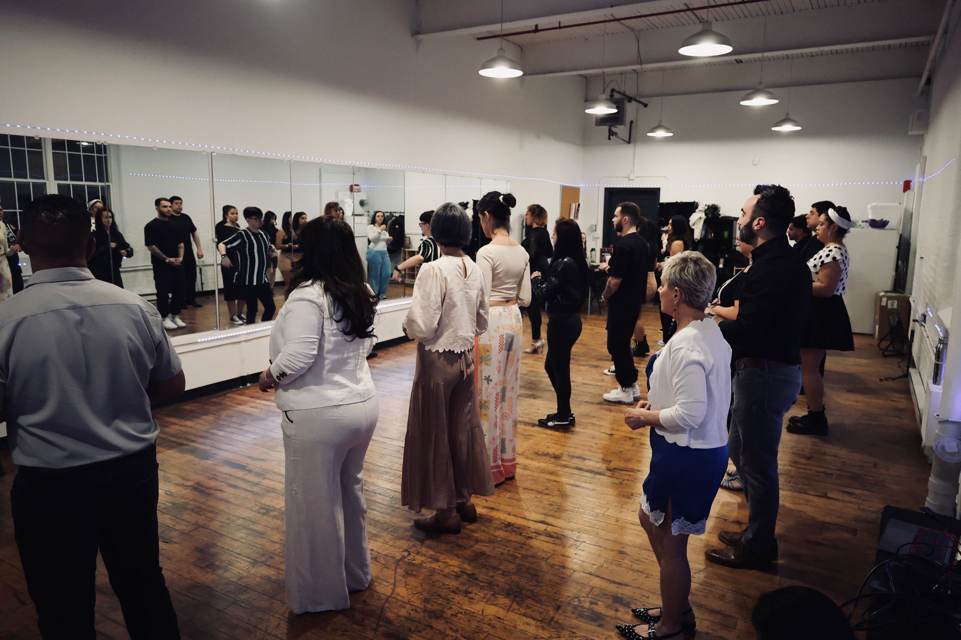 A group of younger and older male and female students stand in lines during a Kizomba workshop.