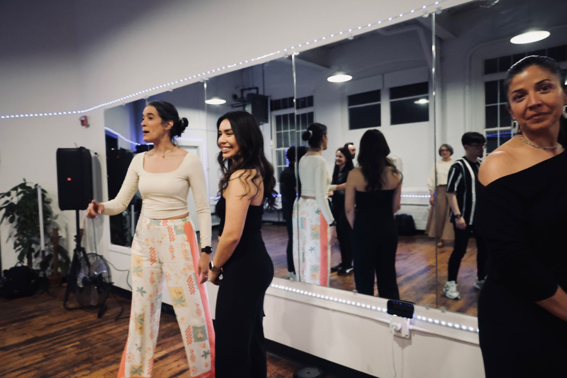 A female students asks a question during a Kizomba workshop as her female dance partner smiles.