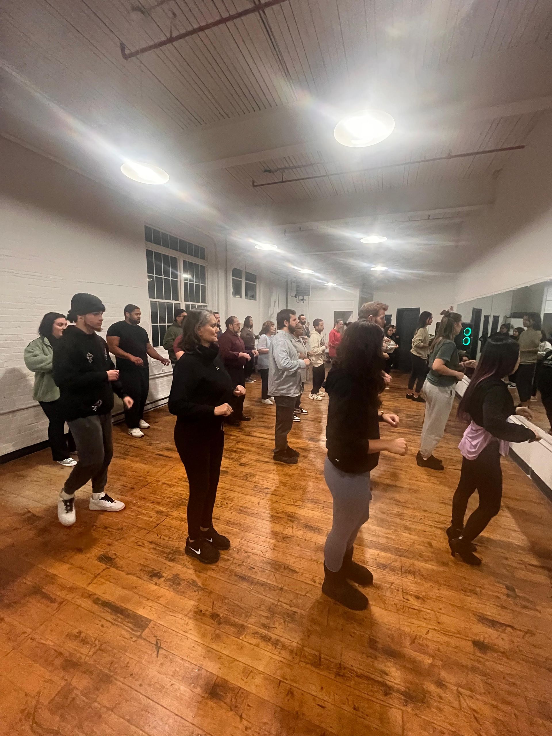 A large group of male and female students stand in lines as their dance class begins.