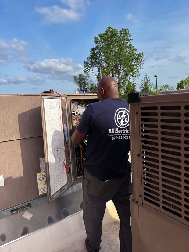 Technician inspecting rooftop HVAC equipment beside a metal unit on a sunny day