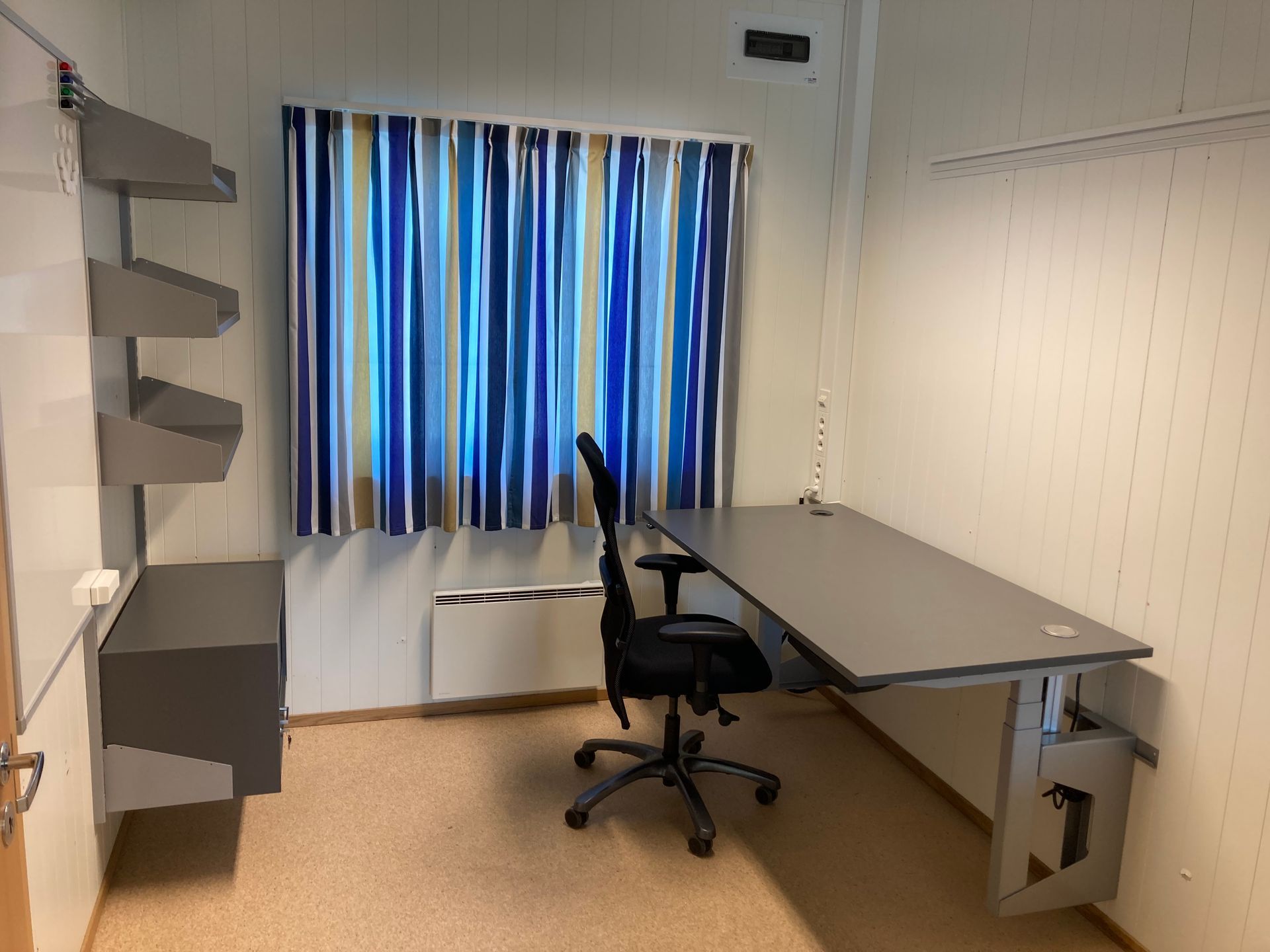 Spisestue med svart bord, oransje stoler og en stor plante. Gang til venstre.