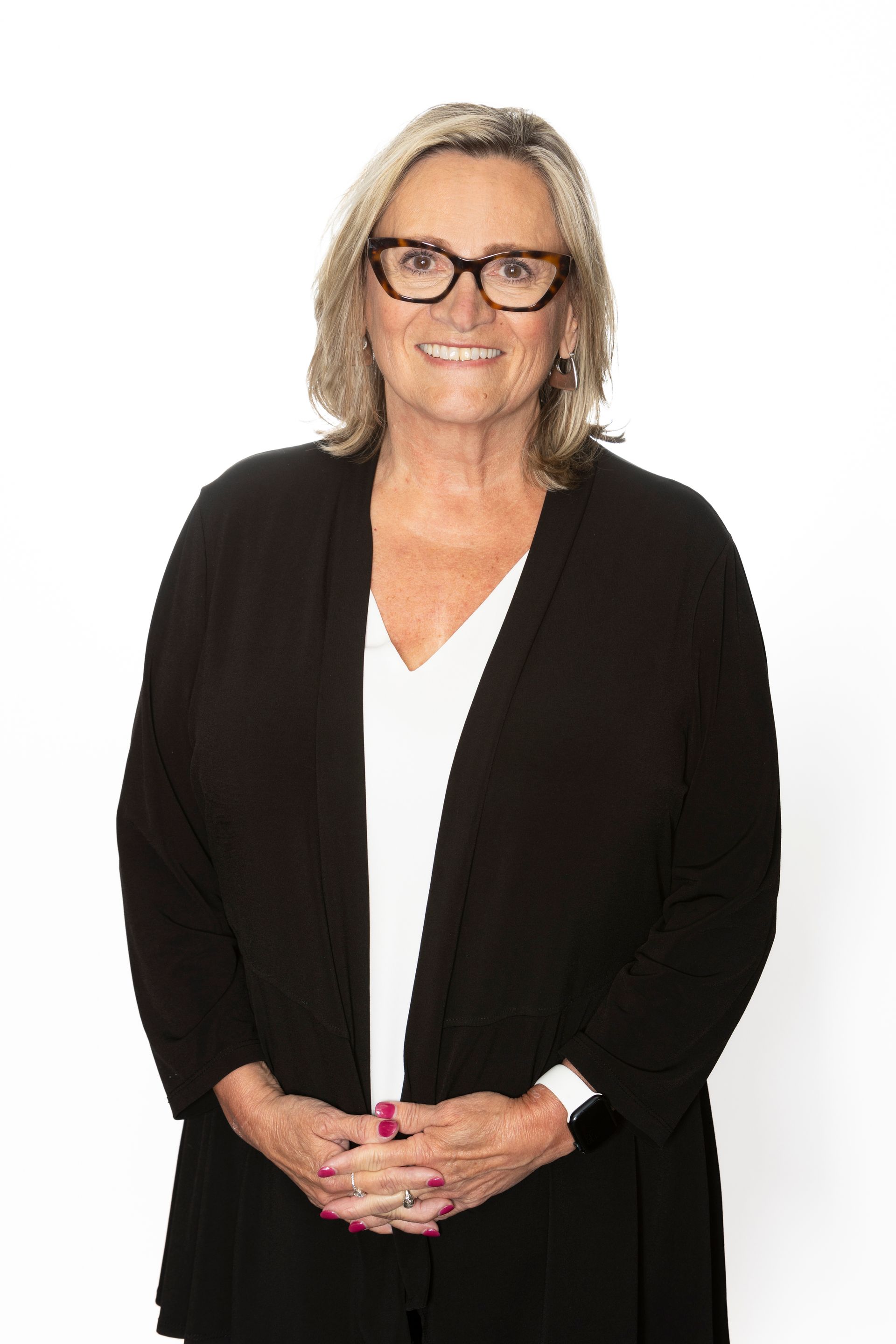 A woman wearing glasses and a purple shirt is smiling for the camera.