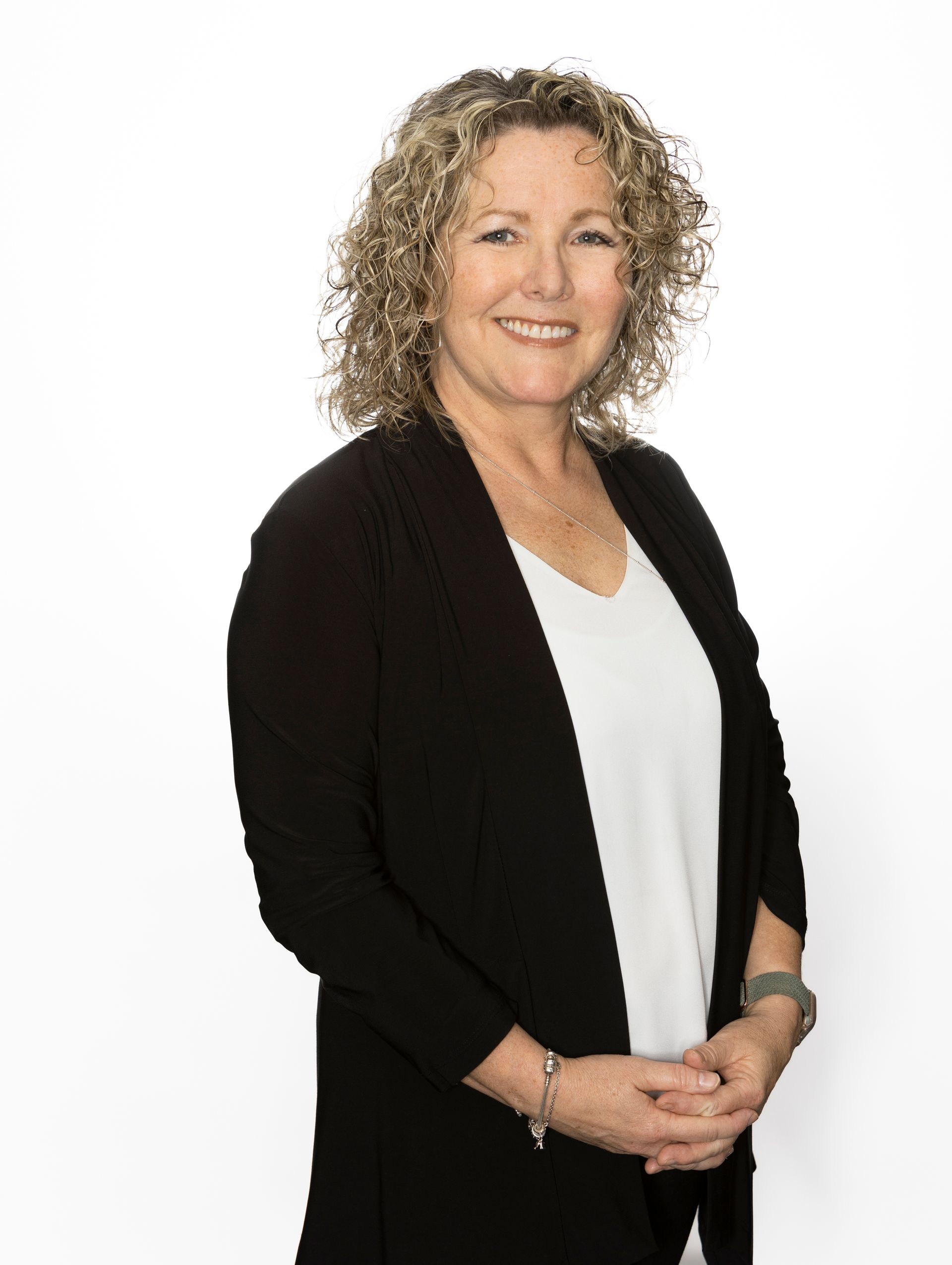 A woman wearing glasses and a black jacket is smiling for the camera.