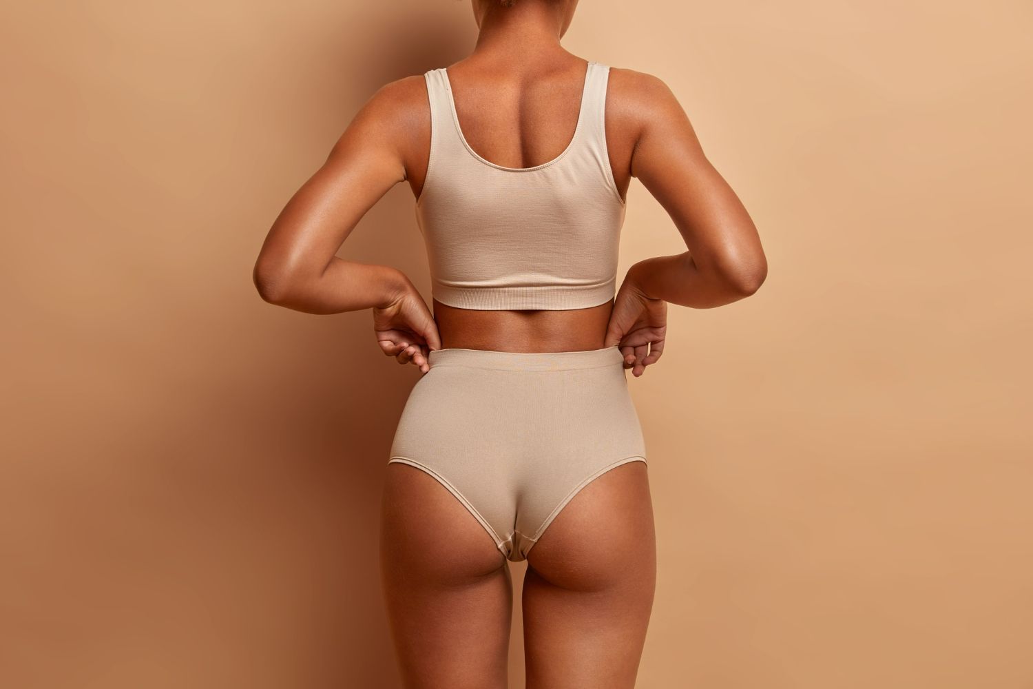 The back of a woman wearing a crop top and high waisted underwear.