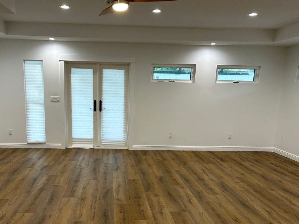 An empty living room with hardwood floors and a ceiling fan.