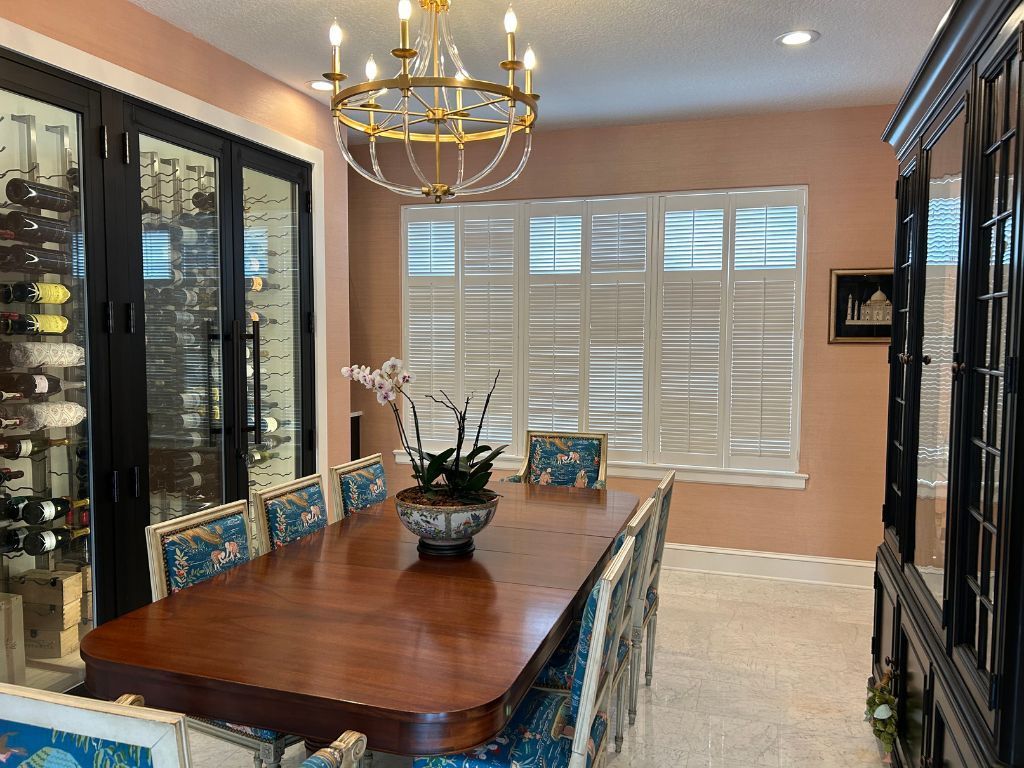 A dining room with a long table and chairs and a chandelier hanging from the ceiling.