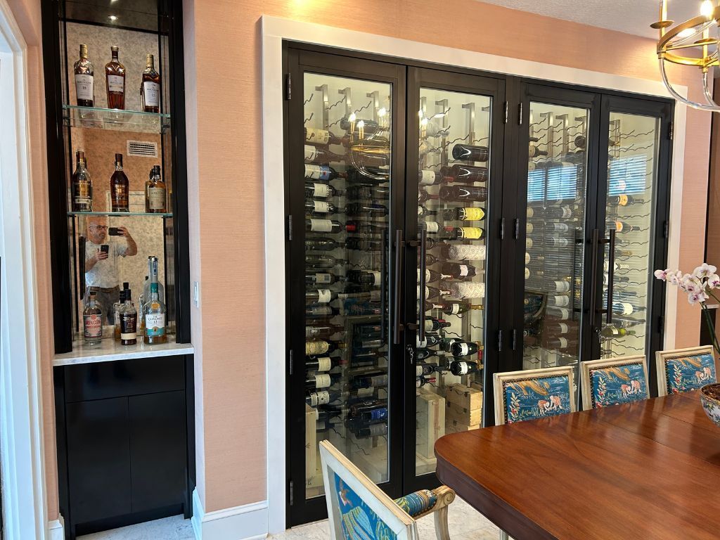 A man is taking a picture of a wine cellar in a dining room.