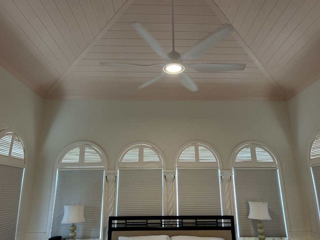 A bedroom with arched windows and a ceiling fan