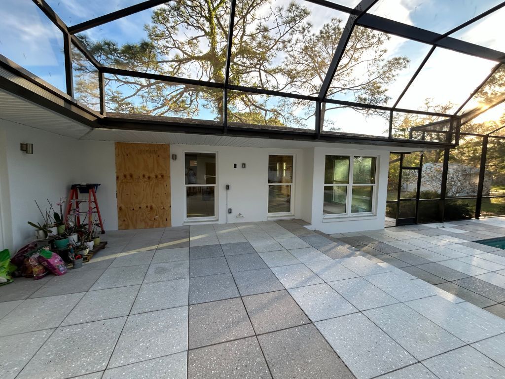 A house with a screened in porch and a ladder in front of it.