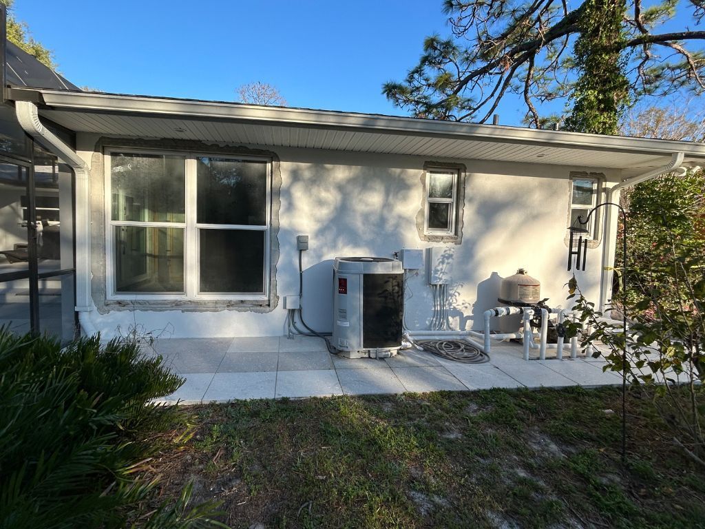 A small white house with a large air conditioner on the side of it.