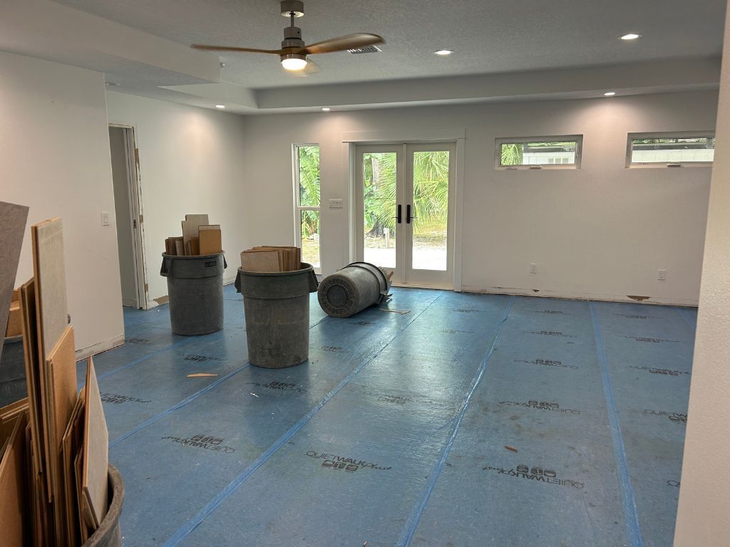 An empty room with a blue floor and a ceiling fan.