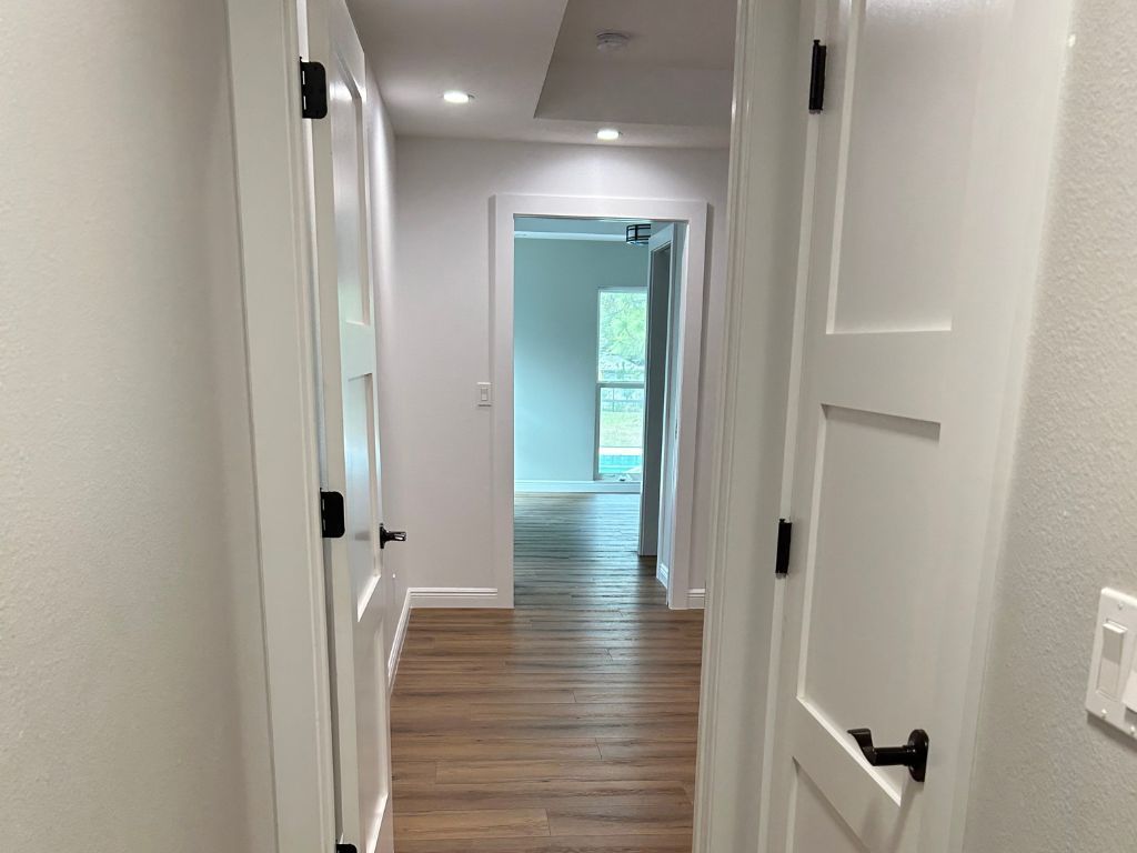 A hallway with white doors and wooden floors in a house.