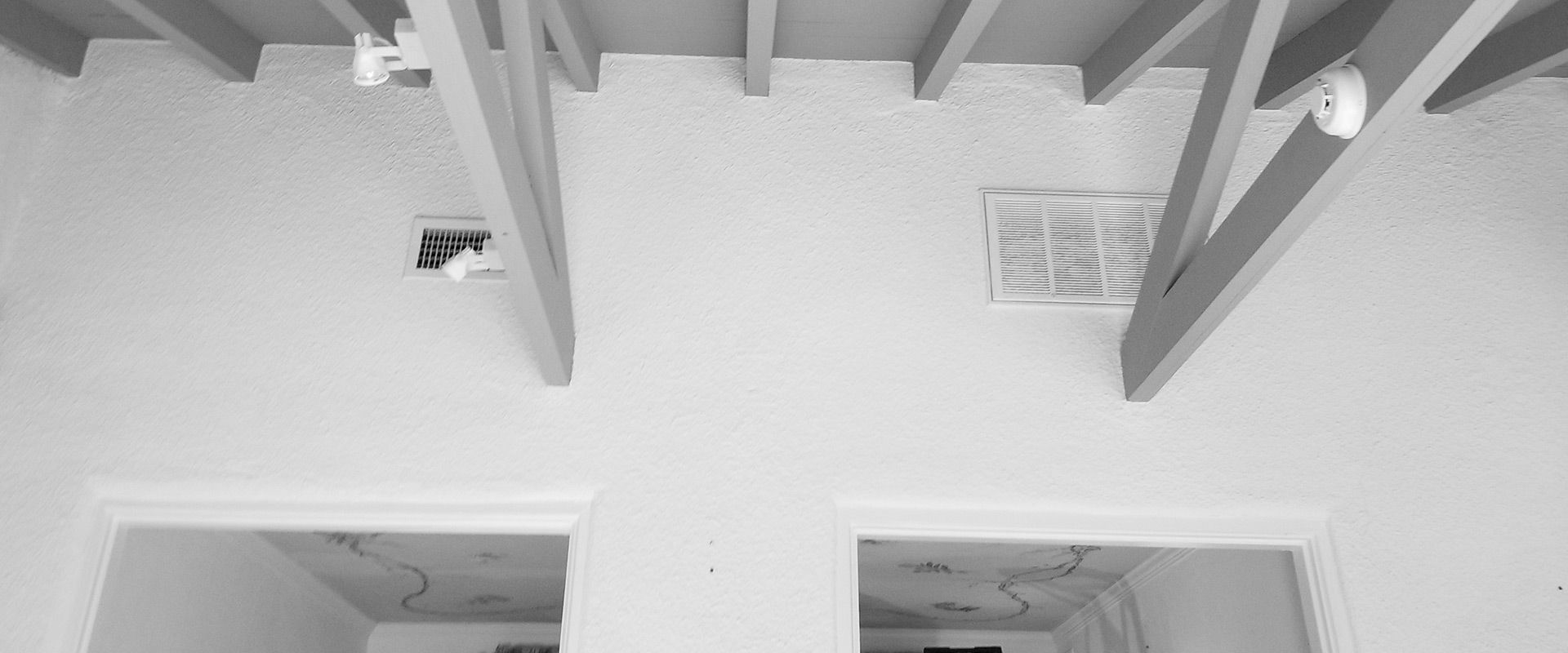 A black and white photo of a ceiling with wooden beams.