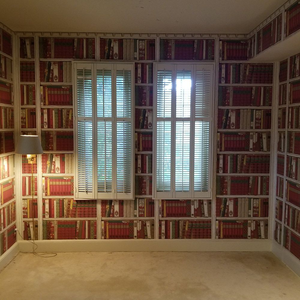 A room with a lot of books on the walls and a window.