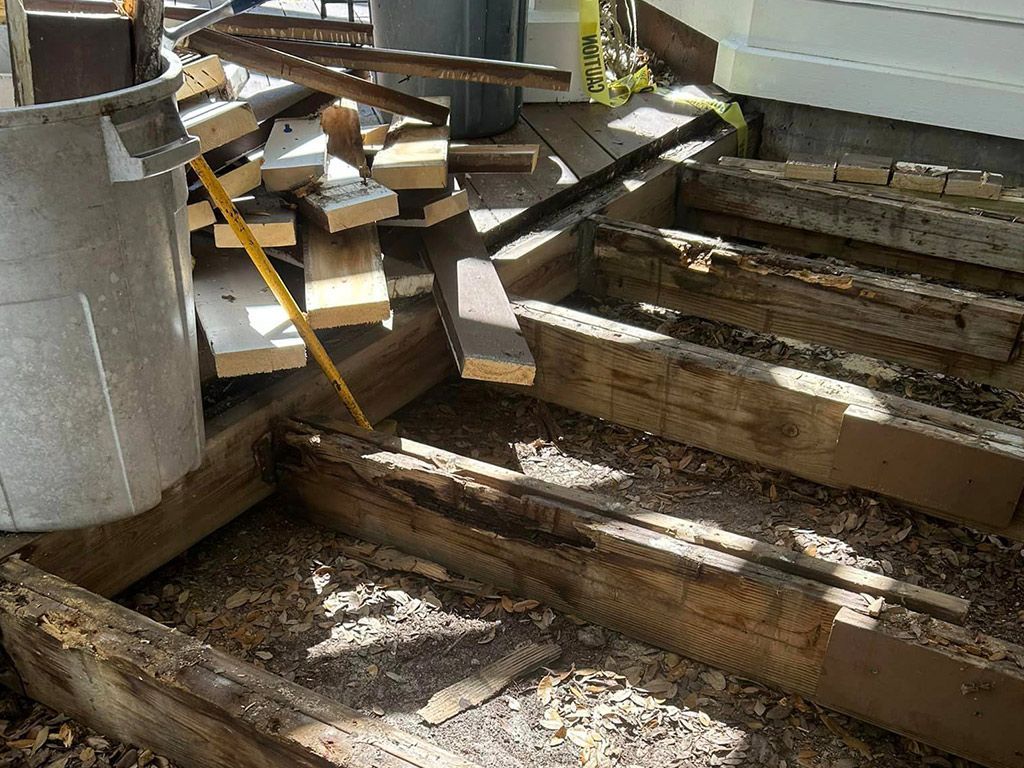 A pile of wood is sitting on the ground next to a metal bucket.