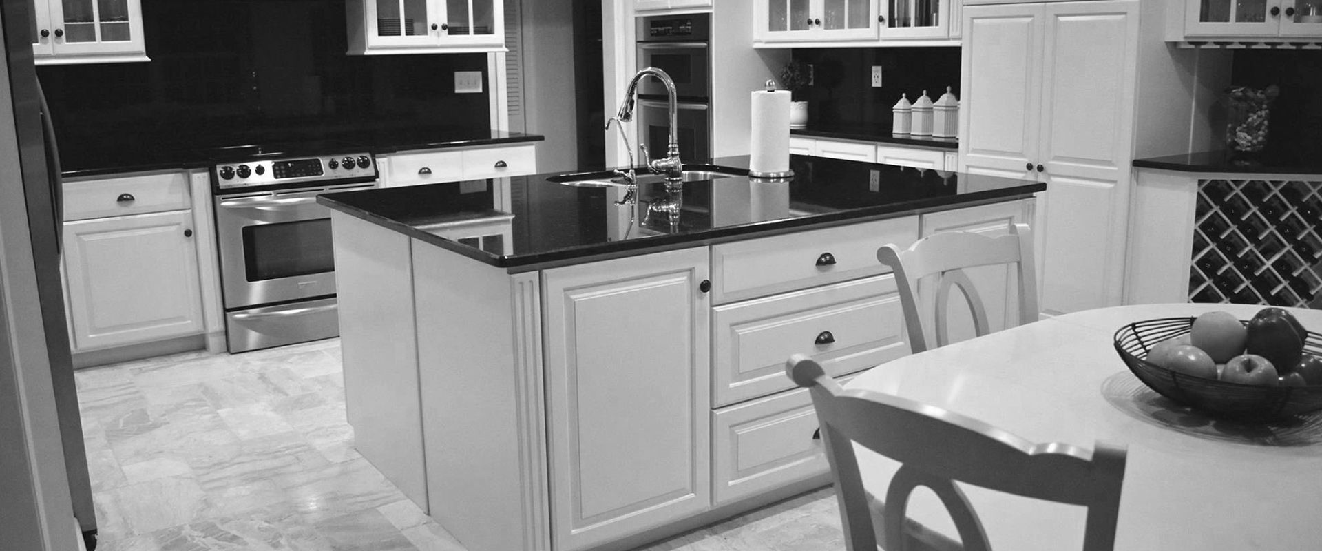 A black and white photo of a kitchen with a table and chairs.
