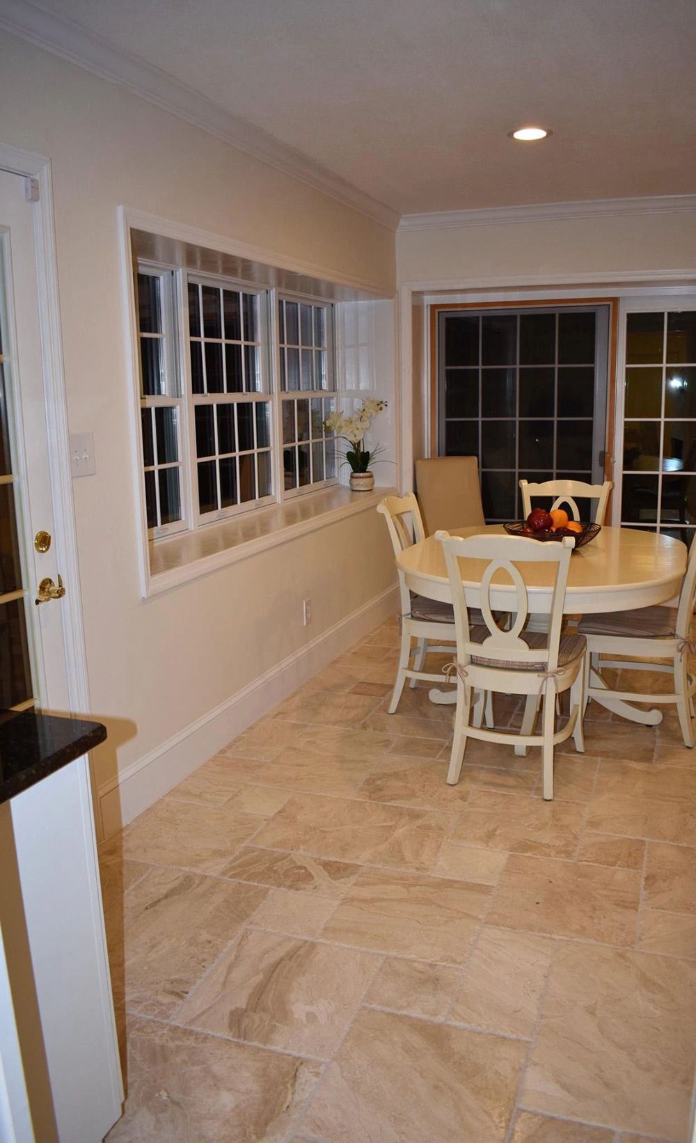 A dining room with a table and chairs and a sliding glass door.